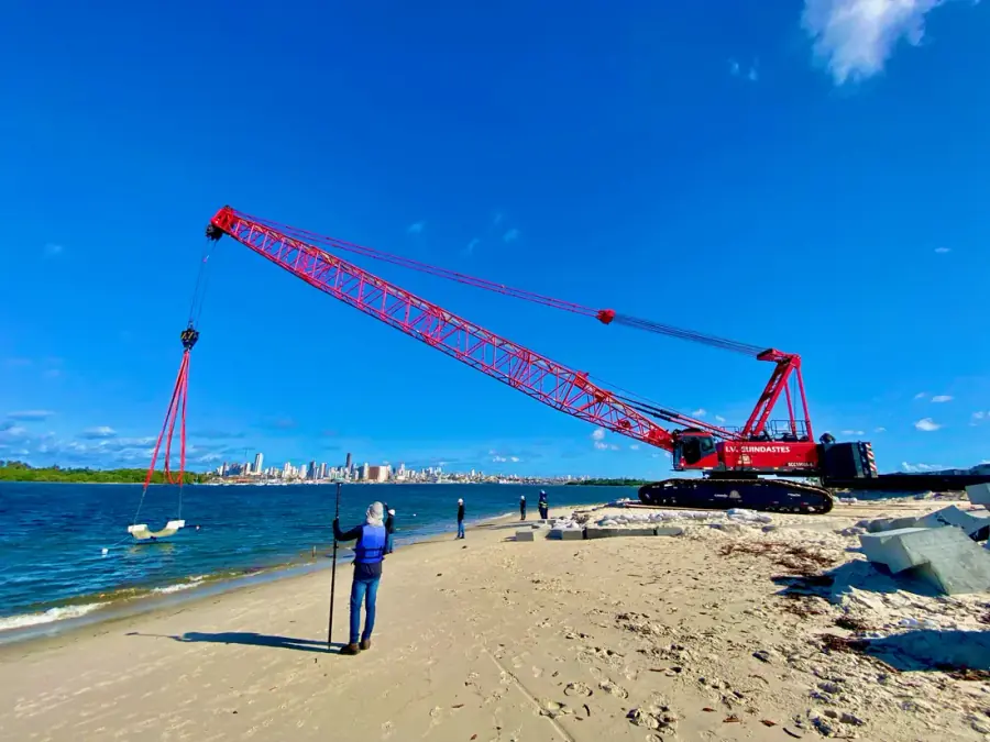 Levantamento batimétrico em obra portuária com guindaste e skyline de Salvador